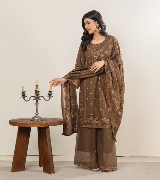 Woman in a brown traditional outfit standing next to a wooden table with a candle holder.